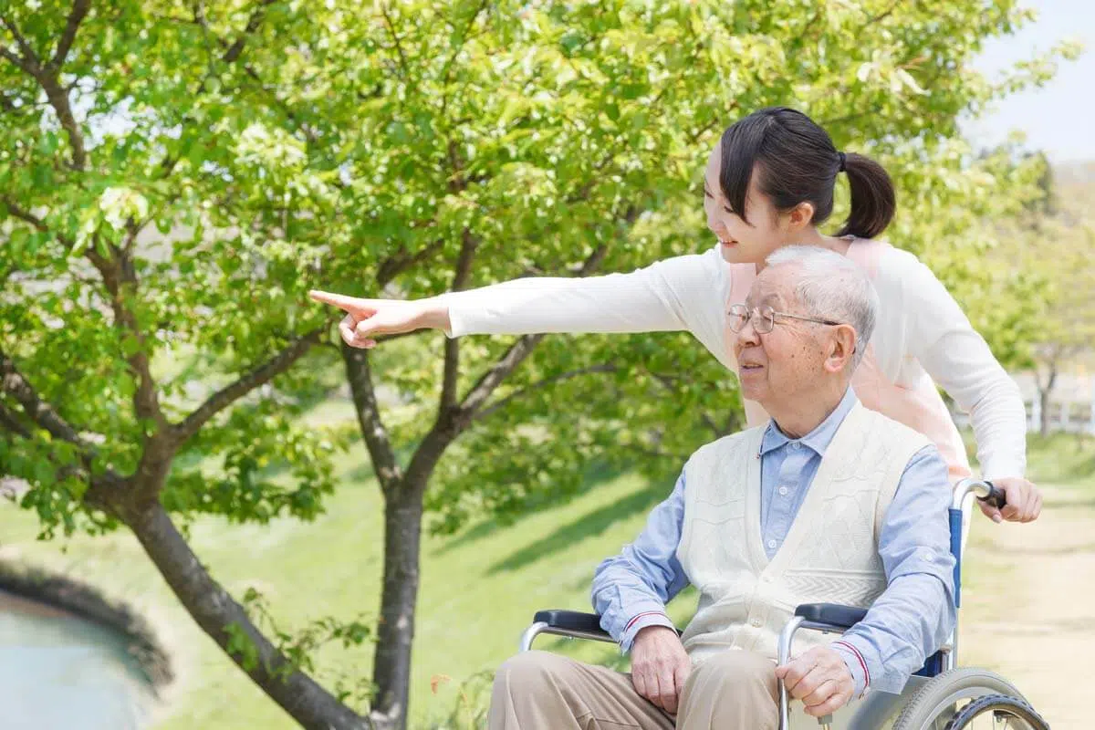家庭幫傭溫柔的推著年長的長輩在公園裡出外散步