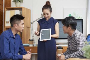 年輕女主管向兩位男同事展示平板上的內容